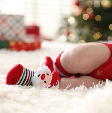 Noel çoraplı bebek. Yatakta. Kapalı alanda bulanık ışıklara karşı.