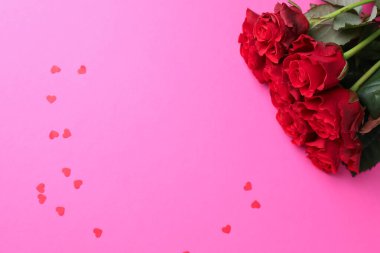 Sevgililer Günün kutlu olsun. Kırmızı gül buketi ve pembe arka planda konfeti. Metin için boşluk