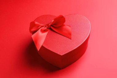 Sevgililer Günün kutlu olsun. Kırmızı arkaplanda kalp şeklinde hediye kutusu, yakın plan.