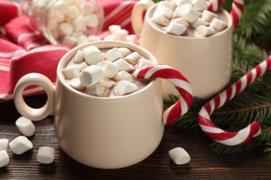 Marşmelovlu lezzetli kakao, baston şekerler ve ahşap masada Noel dekoru, yakın plan.