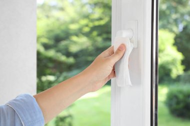 Pencereyi temizleyen kadın, yakın çekim. Yeşil bahçe, camdan manzara