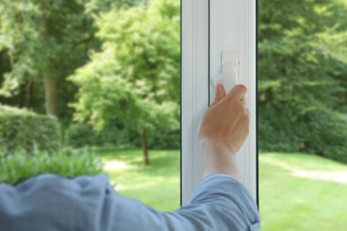 Pencereyi temizleyen kadın, yakın çekim. Yeşil bahçe, camdan manzara