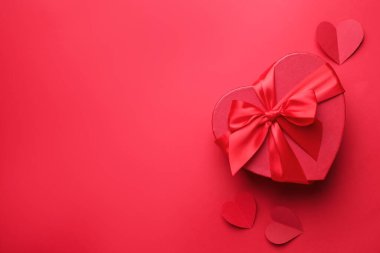 Sevgililer Günün kutlu olsun. Kalp şeklinde hediye kutusu ve kırmızı zemin üzerinde kağıt kalpler, düz yatıyordu. Metin için boşluk