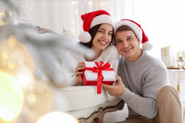 Noel Baba şapkalı mutlu çift evde Noel hediyesiyle