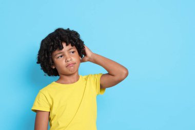 Açık mavi arka planda kafası karışmış küçük bir çocuğun portresi, metin için boşluk