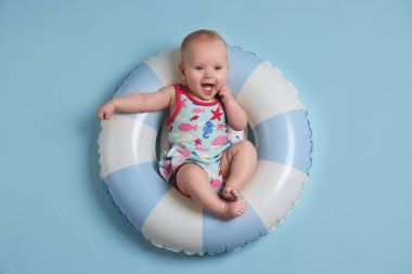 Şişme halkada şirin bir bebek, açık mavi arka planda, üst tarafta.