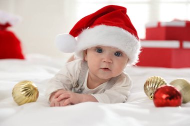Noel Baba şapkalı bebek ve yatakta Noel mücevherleri
