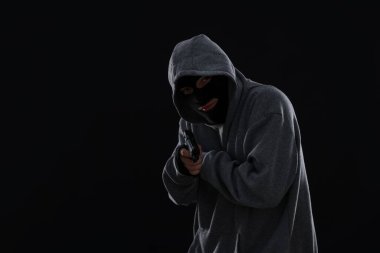 Siyah arka planda silahı olan maskeli bir suçlu, mesaj için yer var.