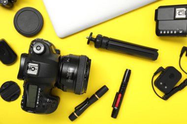 Sarı arka planda profesyonel fotoğrafçı ekipmanı var.