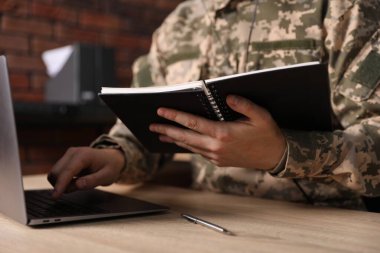 Askerî görevli, odunlukta dizüstü bilgisayarda çalışıyor, yakın plan.