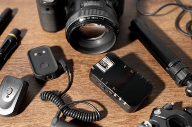 Ahşap arka planda profesyonel fotoğrafçı ekipmanı, yakın plan.