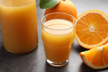 Taze portakal suyu ve meyveler gri masada, yakın plan.