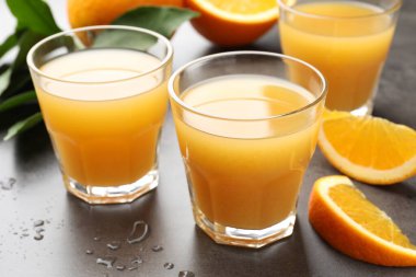 Taze portakal suyu ve meyveler gri masada, yakın plan.