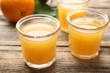 Taze portakal suyu ve ahşap masada meyveler, yakın plan.