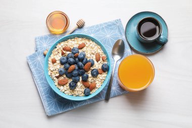 Kuru yulaf, fındık ve yaban mersini kahvaltıda gri ahşap masada servis edilir.