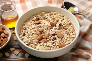 Tahıl yapıyorum. Yulaf gevreği, kurutulmuş meyve, badem fıstığı ve bal ahşap masada, yakın plan.