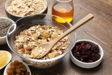 Tahıl yapıyorum. Tahta masada kurumuş meyveli yulaf gevrekleri, yakın plan.