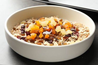 Tahıl yapıyorum. Yulaf ezmeli kase, bal ve kuru meyveler gri masada, yakın plan.