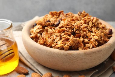 Kurumuş meyveli lezzetli granola ve açık gri masada bal, yakın plan.