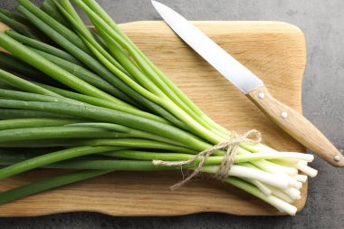 Bir demet taze soğan ve bıçak gri masada, üst tarafta.