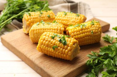 Ahşap masada maydanozlu haşlanmış mısır koçanı parçaları, yakın plan.