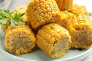 Beyaz masada maydanozlu mısır koçanları, yakın plan.