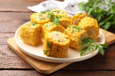 Ahşap masada maydanozlu haşlanmış mısır koçanı parçaları, yakın plan.