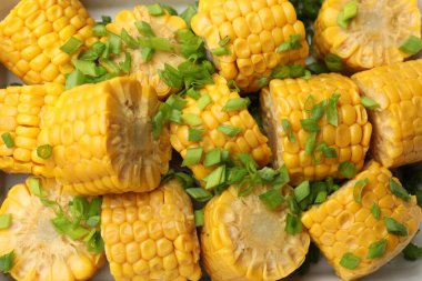 Pişirme kabında yeşil soğanlı haşlanmış mısır koçanı parçaları.