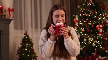 Bir fincan sıcak kakaolu ve noel için dekore edilmiş şekerli ergen kız.