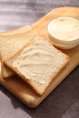 Gri masada tereyağlı ekmek dilimleri, yakın plan.