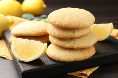 Lezzetli limonlu kurabiyeler ve koyu ahşap masadaki meyve dilimleri, yakın plan.