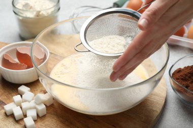 Para kazanmak. Kadın kase içine un eleme ve gri masada farklı malzemeler, yakın çekim