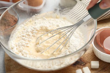 Masada hamuru çırpı ve malzemeyle karıştıran kadın, yakın plan.