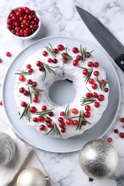 Beyaz mermer masa üzerinde yaban mersinli, biberiyeli, biberiyeli, biberli ve bıçaklı lezzetli bir Noel pastası.