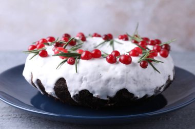 Gri ahşap masada yaban mersinli ve biberiyeli lezzetli Noel pastası, yakın plan.