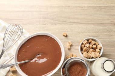Kase içinde sıvı çikolata hamuru, kakao tozu, kahverengi şeker ve süt ahşap masada, düz yatak. Metin için boşluk