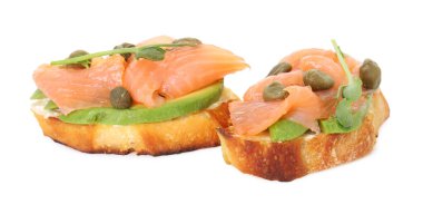 Somon, avokado, kapari ve beyaz üzerine izole edilmiş mikro yeşillikler ile lezzetli bruschetalar.