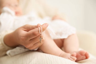 Vaftiz ayini. Kadın kucağında küçük bebek ve altın haç, seçici odaklanma