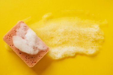 Turuncu arka planda köpüklü mutfak süngeri, üst manzara. Metin için boşluk