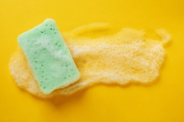 Turuncu arka planda köpüklü mutfak süngeri, üst manzara. Metin için boşluk