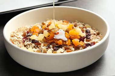 Tahıl yapıyorum. Yulaf gevrekleri ve kurutulmuş meyvelerle kaplara bal dökerek.