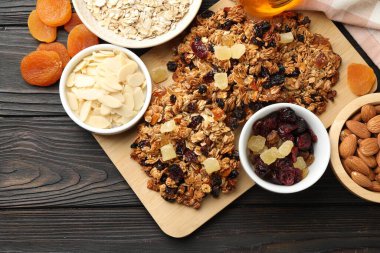 Kurumuş meyveli ve fındıklı lezzetli granola barları, siyah ahşap masa, düz uzanmış