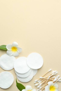 Temiz pamuk pedleri, bej arka planda bezler ve çiçekler, düz yatış. Metin için boşluk