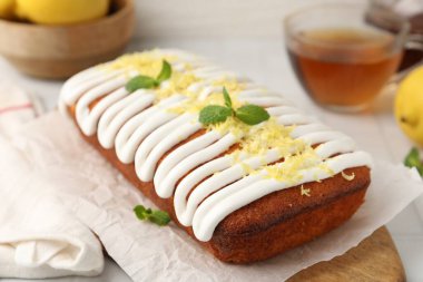 Krema, lezzet ve nane ile süslenmiş lezzetli limonlu pasta beyaz fayanslı masada servis edilir, yakın plan.