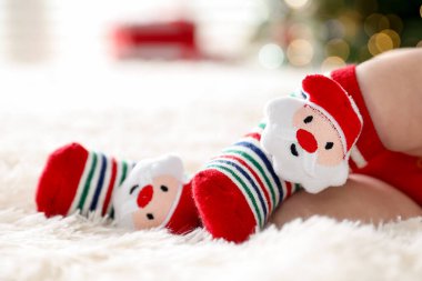 Noel çoraplı bebek, yatağında kapalı alanda bulanık ışıklara karşı, yakın plan. Metin için boşluk