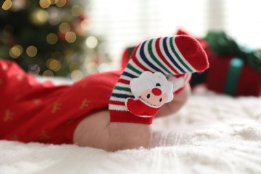 Noel çoraplı bebek. Yatakta. Kapalı alanda bulanık ışıklara karşı.