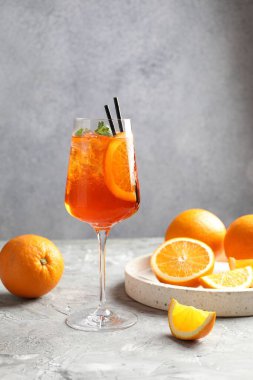 Gri desenli masaya serinletici bir kokteyl ve portakallar.