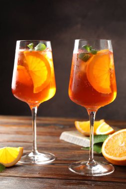 Serinletici spritzer kokteyli ve portakallar ahşap masada.