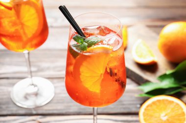 Bardaklar ferahlatıcı spritzer kokteyli ve portakallar ahşap masada, yakın plan.