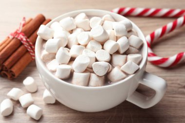 Marşmelovlu lezzetli kakao, şeker kamışı ve ahşap masada tarçın, yakın plan. Noel atmosferi